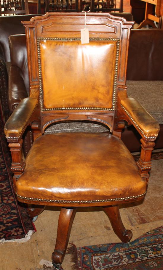 Victorian oak open arm swivel desk chair, upholstered in studded tan hide